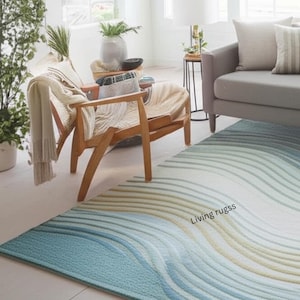 K&ouml;nnte beinhalten: Rechteckiger Teppich mit wellenf&ouml;rmigem Muster in Blau-, Wei&szlig;- und Beiget&ouml;nen. Der Teppich liegt auf einem hellen Boden in einem Wohnzimmer. Der Text "Living rugss" ist auf dem Teppich zu sehen. Das Design wirkt beruhigend.