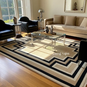May include: A geometric patterned rug with a zig-zag border in a living room. The rug has black, beige, and off-white stripes. The text "Living rugss" is visible on the rug. The room includes a sofa, chairs, and a glass coffee table.