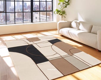 May include: A rectangular area rug featuring a geometric pattern with large blocks of cream, black, tan, and light gray. The design includes curved and straight lines that divide the surface into distinct shapes. The text Living Rugs is visible.