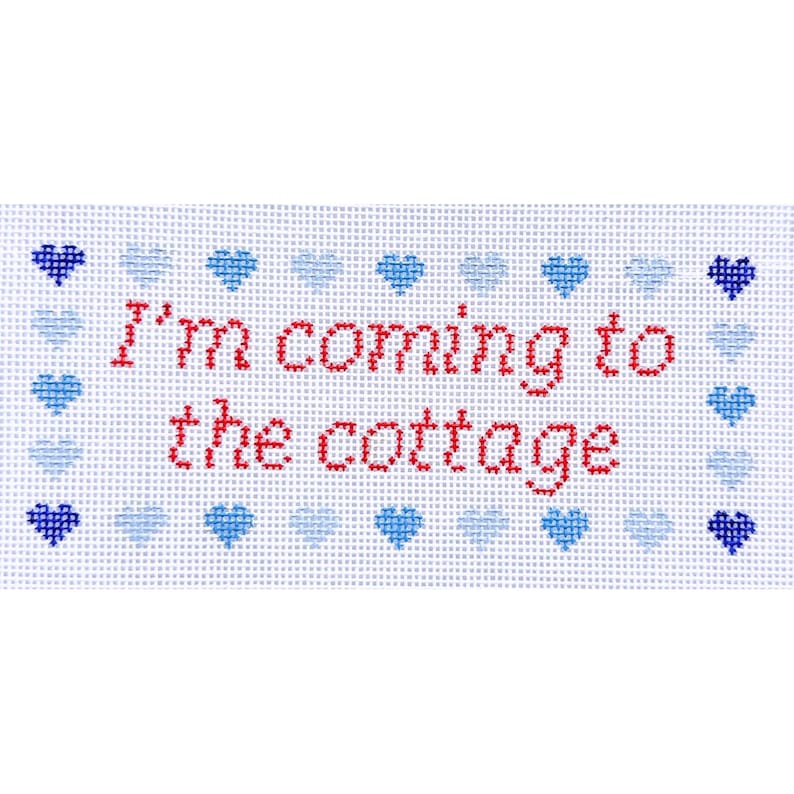 May include: A cross-stitched rectangular piece with the words "I'm coming to the cottage" in red. The text is centered on a white background, framed by a border of blue hearts.