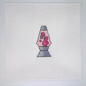 May include: A cross-stitch design of a pink lava lamp with a gray base and top, set against a white, grid-like background. The lava lamp features a pink, blob-like design inside. The artwork is square and centered.