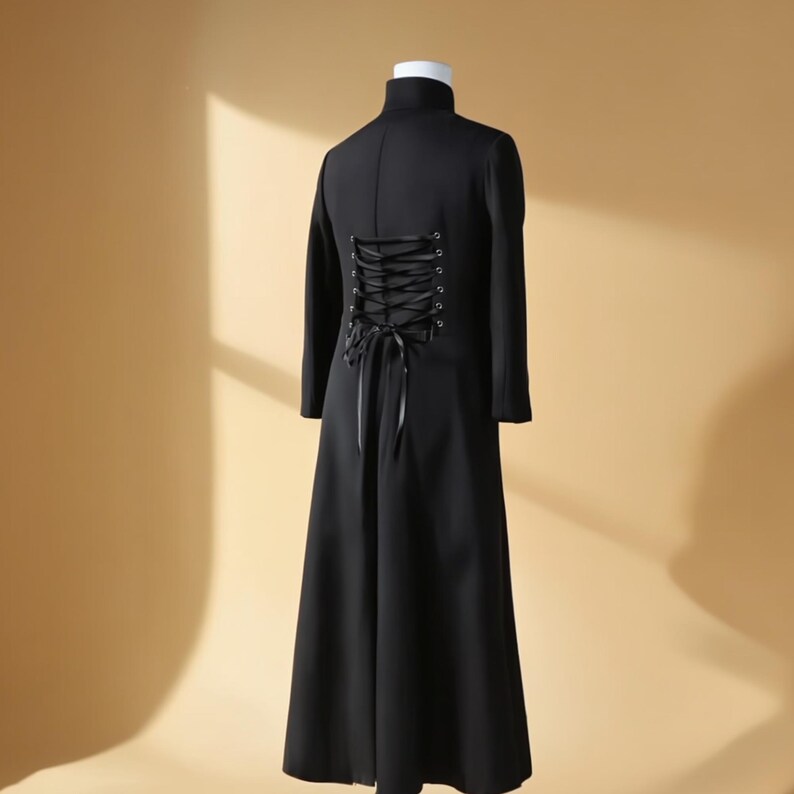 May include: A long, black coat with a high collar and long sleeves. The back features a corset-style lace-up design. The coat is displayed on a mannequin against a neutral background, showcasing its tailored silhouette and gothic aesthetic.