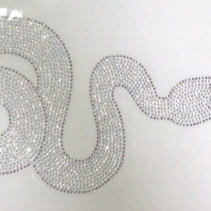 Pode incluir: Um design de cobra de strass prateado, perfeito para adicionar um toque de brilho a roupas ou artesanato.