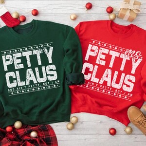 May include: Two Christmas sweatshirts, one green and one red, with the text "Petty Claus" in white. The green sweatshirt says "God ain't petty, but I am." The red sweatshirt says "Ms. Petty Claus, I ain't petty, but I am."