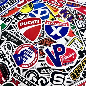 May include: A collection of colorful racing and automotive-themed stickers. The stickers feature various logos, including "Ducati," "Racer X," and "VP Racing Fuels." The designs incorporate red, white, blue, and black, with bold typography and graphic elements.