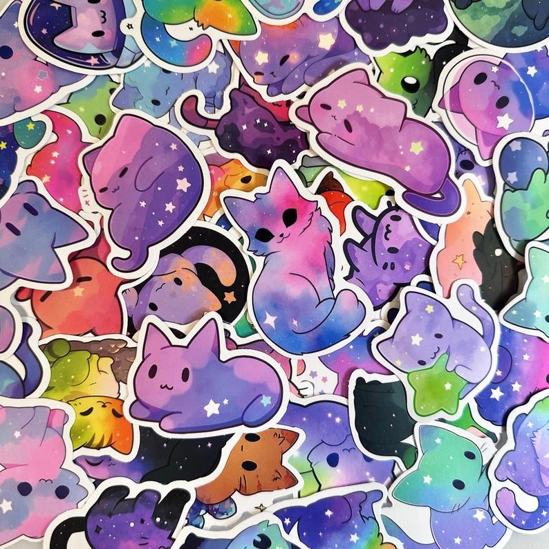 K&ouml;nnte beinhalten: Eine Sammlung bunter Katzenaufkleber mit Galaxiethema. Die Aufkleber zeigen verschiedene Katzendesigns in Rosa-, Lila-, Blau- und Gr&uuml;nt&ouml;nen mit Sternakzenten. Die Aufkleber sind in einem zuf&auml;lligen Muster angeordnet.