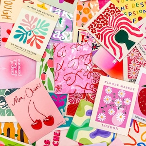 May include: A collection of colorful art prints with various designs. Some prints feature floral arrangements, abstract shapes, and text like "Flower Market London" and "Mon Ch&eacute;ri". The color palette includes pinks, greens, reds, and oranges.
