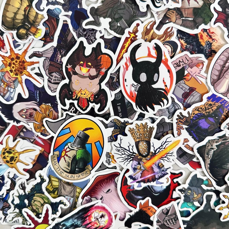 May include: A selection of vibrant stickers showcasing fantasy characters and designs. The stickers depict knights, demons, and other fantastical creatures. Some stickers include text, such as "May the Sun Shine".