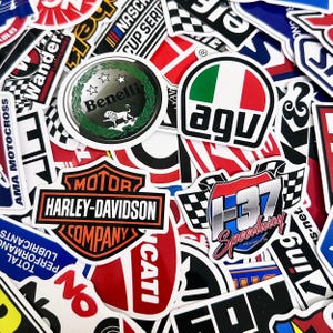 May include: A collection of colorful stickers featuring various logos and designs. Prominent stickers include the Harley-Davidson logo, a Benelli emblem, and an AGV logo with the Italian flag colors. Other stickers display racing and automotive themes.