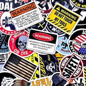 May include: A collection of various stickers with bold graphics and text. The stickers feature warnings, skulls, the American flag, and phrases like "Do Not Touch My Tools" and "Think Safety First." The color palette includes red, black, yellow, and white.