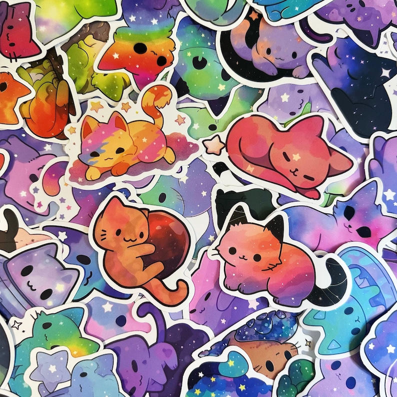 K&ouml;nnte beinhalten: Eine Sammlung farbenfroher Katzenaufkleber mit Galaxiethema. Die Aufkleber zeigen verschiedene Katzendesigns in Rosa-, Orange-, Lila- und Blaut&ouml;nen mit Sternen und anderen himmlischen Elementen. Die Aufkleber sind eng angeordnet.