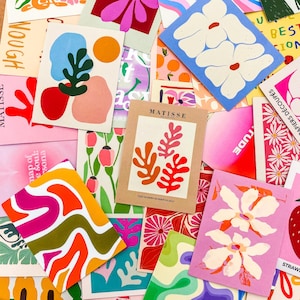 May include: A collection of colorful art prints with abstract designs and floral patterns. The prints feature various shapes, colors, and text, including the word "MATISSE". The color palette includes pink, orange, blue, and green.