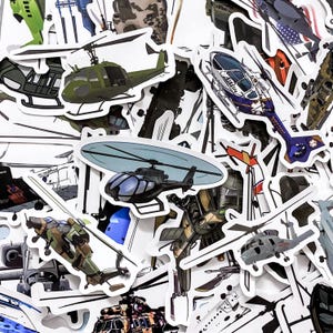 May include: A selection of helicopter stickers in various colours and designs. The stickers feature detailed illustrations of different types of helicopters, including military and civilian models. Some stickers have a glossy finish.