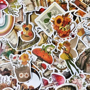 May include: A selection of whimsical stickers with diverse designs. Includes a guitar decorated with flowers, a frog on a mushroom, a fairy, a teacup overflowing with sunflowers, and a postage stamp with the text "Postina 50".