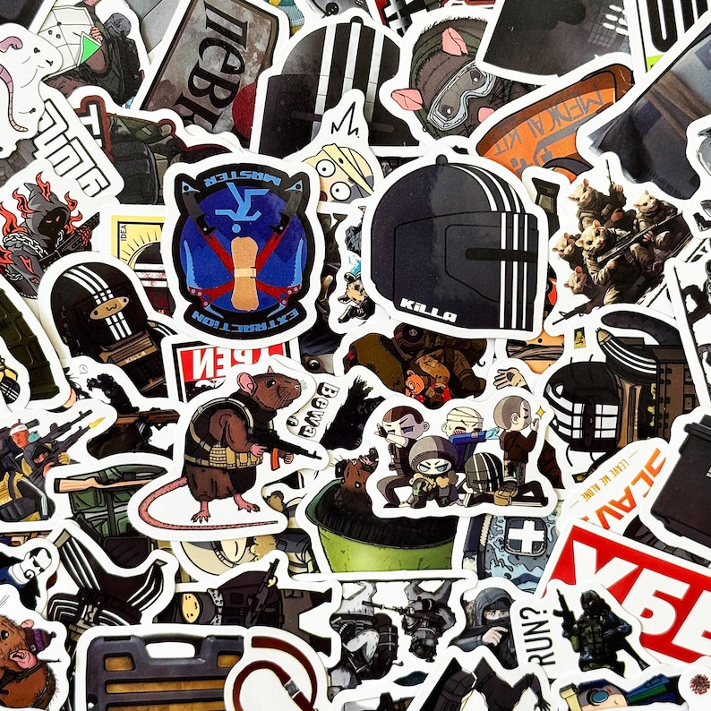 Puede incluir: Una colecci&oacute;n de pegatinas variadas con ilustraciones de temas militares y t&aacute;cticos. Las pegatinas incluyen im&aacute;genes de cascos, soldados y una rata con un arma. Algunas pegatinas tienen texto, incluyendo "KILLA" y "RUN?"
