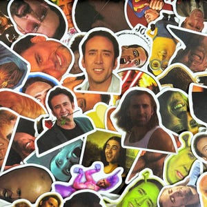 May include: A collection of die-cut stickers featuring various images of actor Nicolas Cage. The stickers showcase different expressions and poses, with a variety of colors and styles. Some stickers include images of other people.