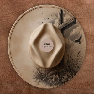 May include: A tan fedora-style hat with a wide brim. The hat features a detailed illustration of a wooden cross, birds, and foliage. The text "PNG Digital File" is printed on the hat.