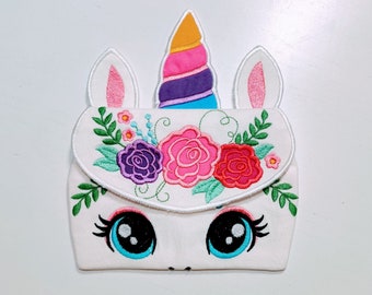 Puede incluir: Bolsa de unicornio de tela blanca con detalles bordados. La bolsa presenta un cuerno de unicornio rosa y azul, orejas rosas y un diseño floral con rosas rosas, moradas y rojas.