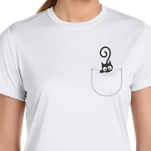 Puede incluir: Camiseta blanca con un gato negro asomándose de un bolsillo en la parte delantera.