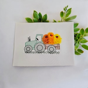 May include: A green tractor with a yellow and orange chick in the bed of the truck. The tractor has black wheels and a brown bed.