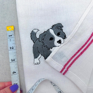 May include: A set of three ceramic mugs with a speckled, cream-colored glaze. Each mug features a different hand-painted design: a blue and green leaf, a yellow flower, and a red berry. The mugs have a simple, rounded shape.