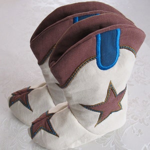 May include: A pair of brown and white cowboy boot slippers with blue trim and a brown star on each boot.