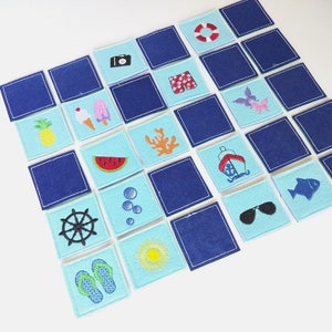 以下が含まれることがあります： 白い背景に様々な刺繍が施された青いフェルトの正方形20枚のセット。画像には、カメラ、サングラス、パイナップル、スイカ、船、サンゴ、ライフセーバー、アイスキャンディー、泡、ビーチサンダル、ハンドル、太陽、水着などが含まれています。