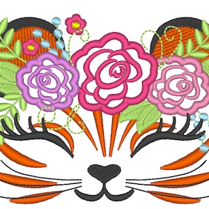 Può includere: Disegno ricamato di un viso di gatto con fiori rosa, viola e verdi intorno alle orecchie. Il gatto ha la pelliccia arancione, gli occhi neri e un naso rosa.