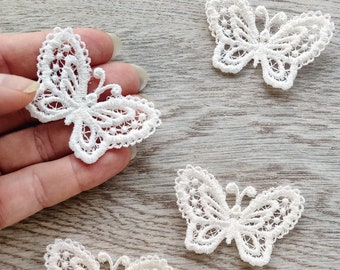Puede incluir: Cuatro apliques de mariposa de encaje blanco. Las mariposas son delicadas e intrincadas, con un diseño detallado.