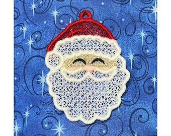 May include: White and red embroidered Santa Claus ornament with a white beard and a red hat. The ornament is on a blue background with white swirls.
