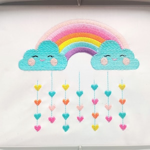 May include: Embroidered design of a rainbow with two smiling clouds and a string of colorful hearts hanging from the clouds.