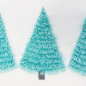 Puede incluir: Tres árboles de Navidad turquesa bordados sobre un fondo blanco. Los árboles tienen un aspecto texturizado y difuso, con troncos de color gris oscuro. El diseño es sencillo y festivo, adecuado para la decoración navideña.