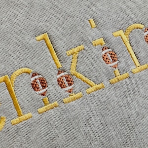 May include: Embroidered "orking" with football designs in yellow thread on a gray sweatshirt.