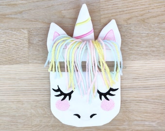 Puede incluir: Bolsa con cremallera en forma de unicornio blanco con un cuerno rosa, pelo de lana amarillo y azul claro y ojos y mejillas bordados.
