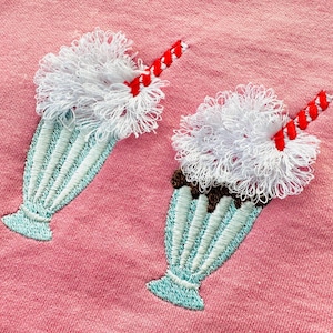 May include: Two embroidered milkshake patches with white whipped cream, red and white straws, and blue and white striped glasses.