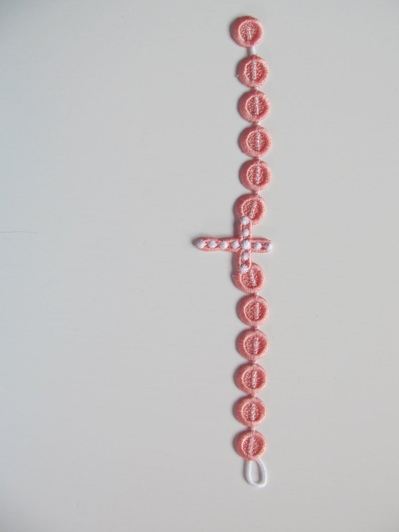 May include: A pink beaded rosary with a white cross charm.