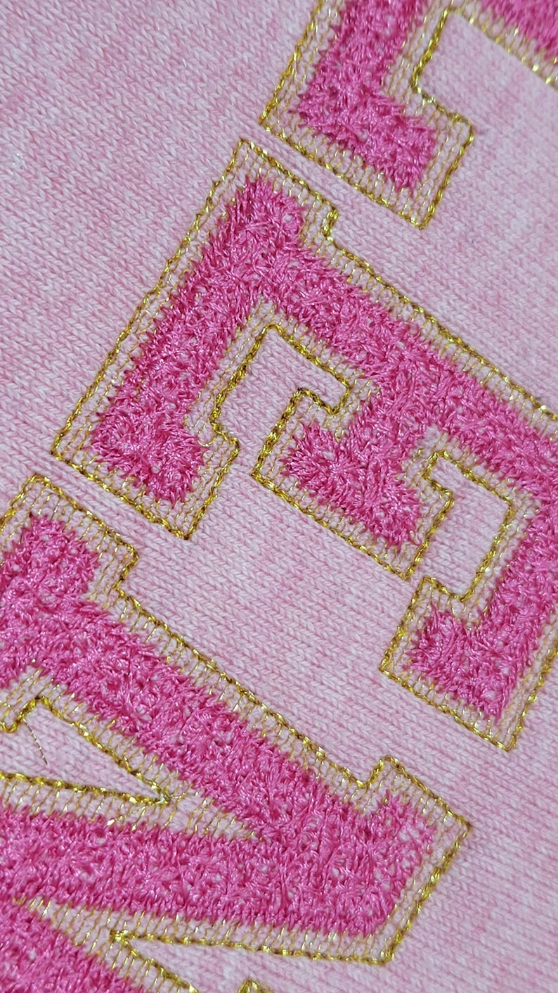 May include: Pink sweatshirt with a gold embroidered "LOVE" on the front.