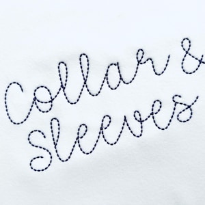 May include: White fabric with the embroidered text "Collar & Sleeves" in navy blue thread. The cursive text is stitched in a continuous line, creating a delicate and elegant design. The background is a plain white.
