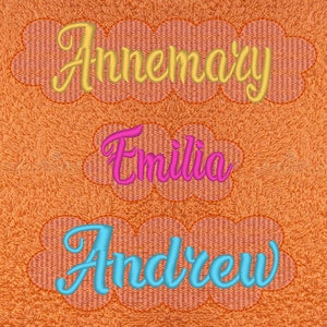 May include: Three embroidered names in a cloud shape. The names are Annemary in gold, Emilia in pink, and Andrew in blue.