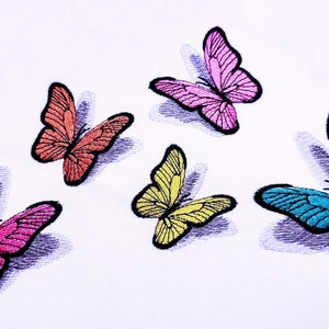 Könnte beinhalten: Fünf gestickte Schmetterlinge in verschiedenen Farben und Designs auf weißem Hintergrund. Die Schmetterlinge sind rosa, orange, gelb und blau.