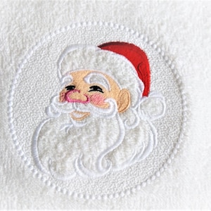 May include: White embroidered towel with a red and white Santa Claus face in a circle.