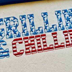 Puede incluir: Tela bordada con el texto "Grillin' & Chillin'" en rojo, blanco y azul. Las letras están rellenas con un patrón de estrellas.