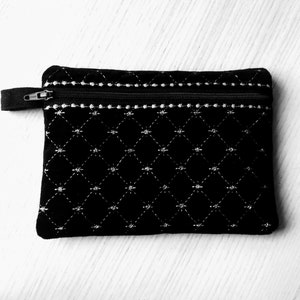 May include: A black quilted zippered pouch with a white diamond pattern.