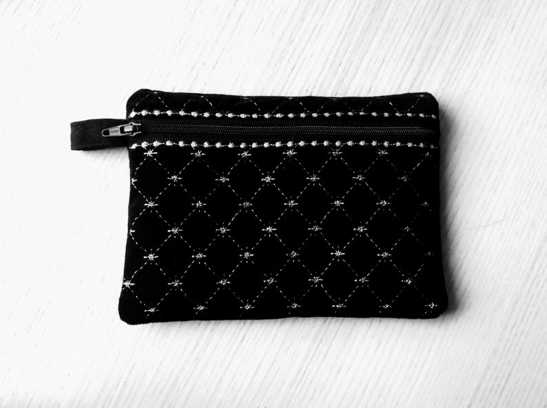 May include: A black quilted zippered pouch with a white diamond pattern.