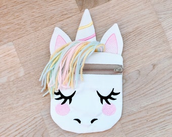 Puede incluir: Bolsa blanca con cremallera en forma de unicornio con una crin de hilo arcoíris, orejas rosas y ojos y nariz bordados.