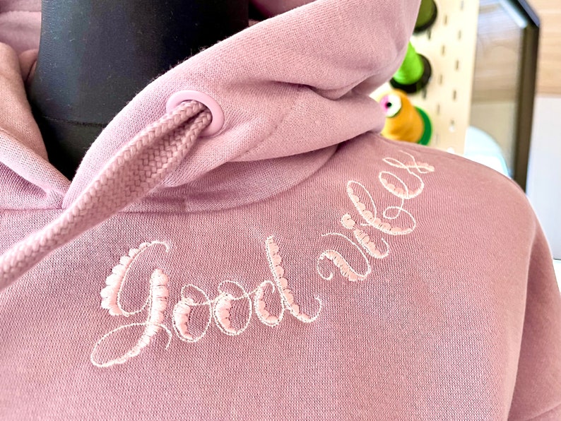 May include: A mauve hoodie with a white embroidered design that says "Good vibes".