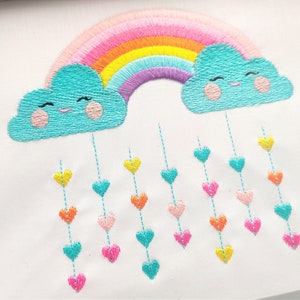 May include: Embroidered design of a rainbow with two clouds, each with a smiling face.  Hearts of various colors hang from the clouds.