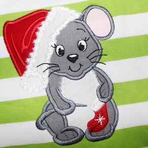 May include: A grey mouse wearing a red and white Santa hat holds a red stocking with a white snowflake. The mouse is embroidered on a green and white striped fabric.