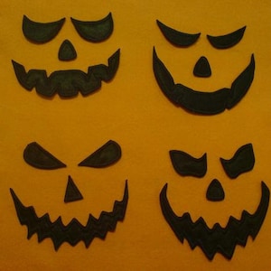 May include: Four black felt Halloween jack-o'-lantern face appliques with different expressions. The faces are cut out and have a stitched edge.