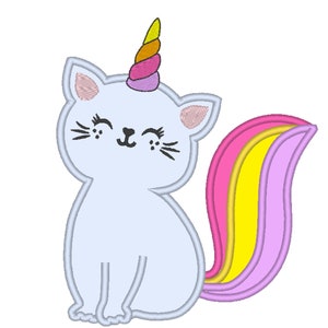 Puede incluir: Un gato azul claro con un cuerno de unicornio rosa, amarillo y naranja y una cola de arcoíris. El gato está sentado con las patas metidas debajo del cuerpo y tiene una expresión feliz.